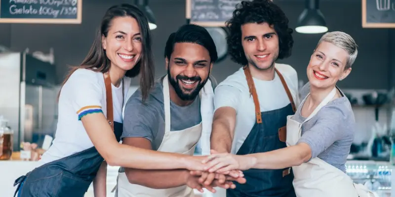 Four employees' hand together smiling at camera
