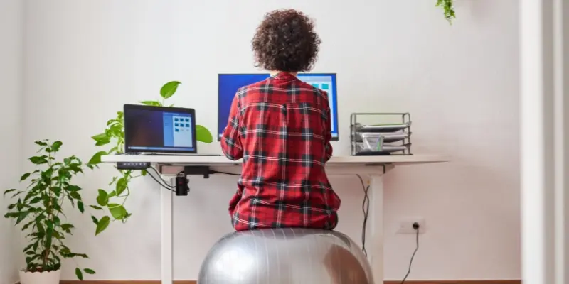 Business owner working at her standing desk while sitting on a yoga ball