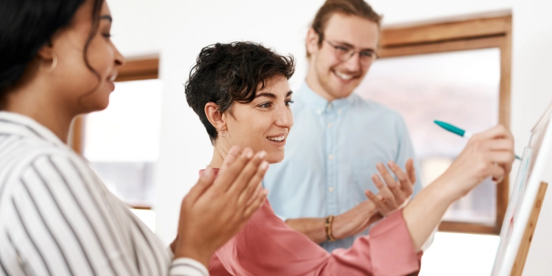 Employees applauding their peer who is writing notes on a white board