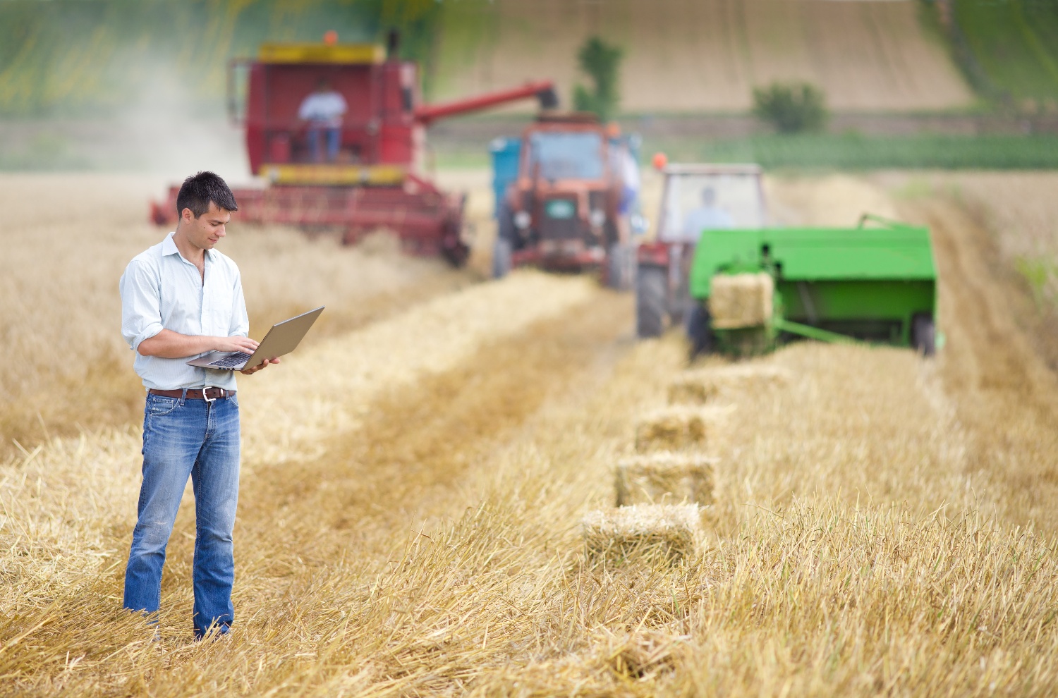 farmer on laptop with tractors in background-1