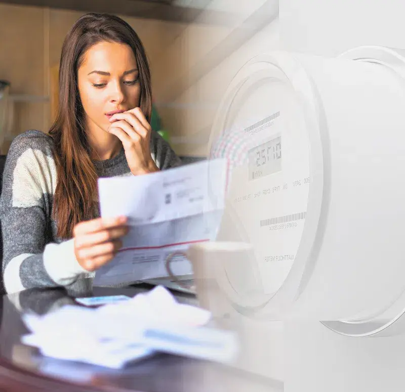 Image of a worried small business owner reading her electricity bill beside an electricity counter