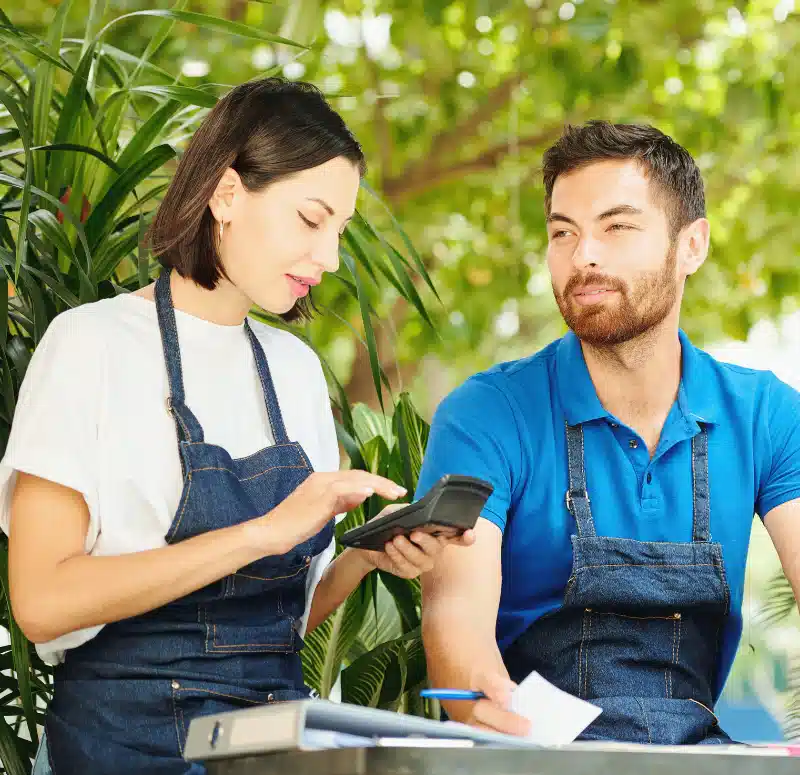 Two small business owners calculating their costs with a calculator